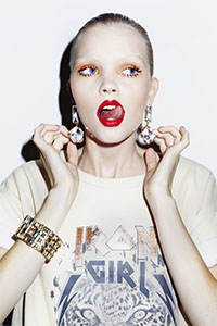 Foto van een punky model met make-up van fel rode lippen en oranje oogschaduw. 